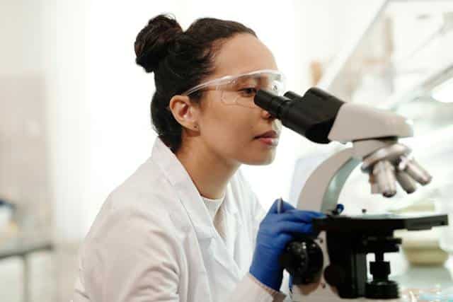 Woman in a lab looking through a microscope
