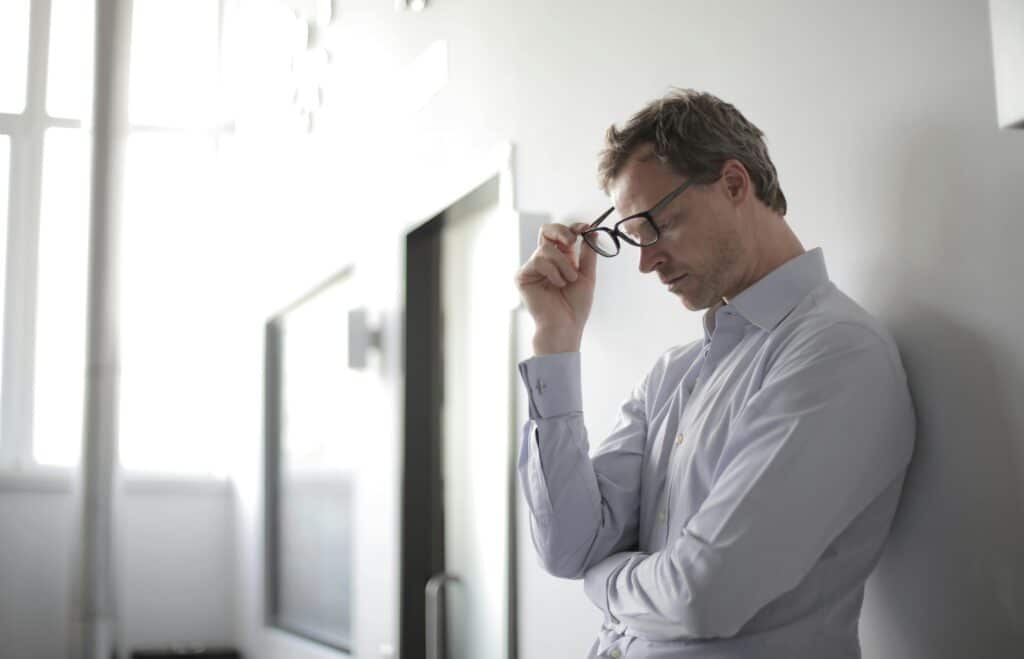 Man leaning against wall looking stressed